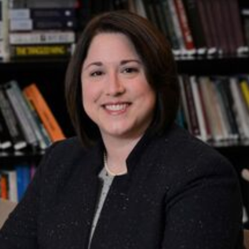 Antoinette B. Coe portrait image. Antoinette B. Coe, head and shoulders, in a dark jacket in front of a bookshelf.