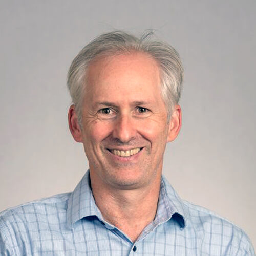 Geoffrey Hoffman portrait image. Geoffrey Hoffman head-and-shoulders portrait. Geoffrey wears a light blue patterned shirt and is pictured in front of a light gray background.